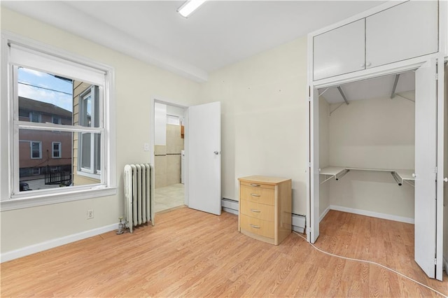 unfurnished bedroom with radiator, baseboards, light wood finished floors, a closet, and a baseboard heating unit