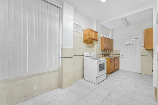 kitchen featuring light tile patterned floors, tile walls, white electric range oven, and light countertops