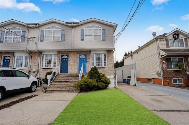 townhome / multi-family property with a front yard and brick siding