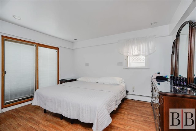 bedroom featuring a baseboard heating unit and wood finished floors