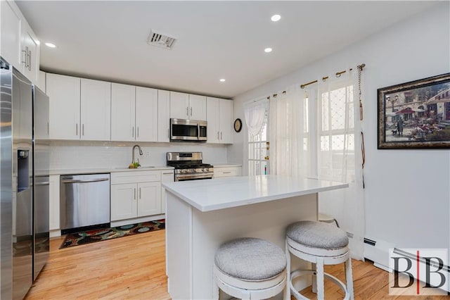 kitchen featuring light countertops, appliances with stainless steel finishes, light wood-style floors, white cabinets, and a sink