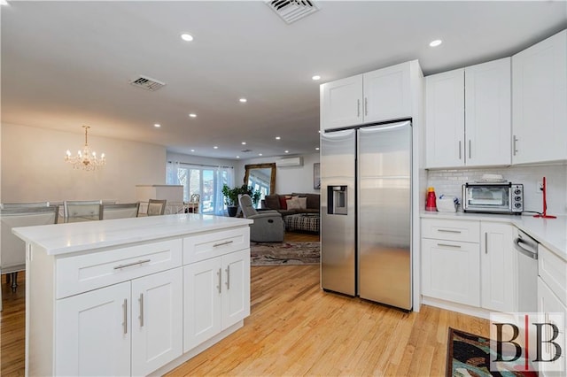 kitchen with a toaster, visible vents, stainless steel fridge, and open floor plan