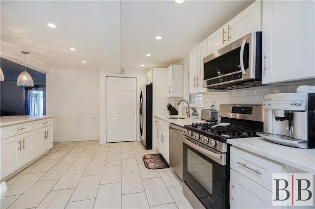 kitchen featuring decorative backsplash, appliances with stainless steel finishes, white cabinetry, and a sink