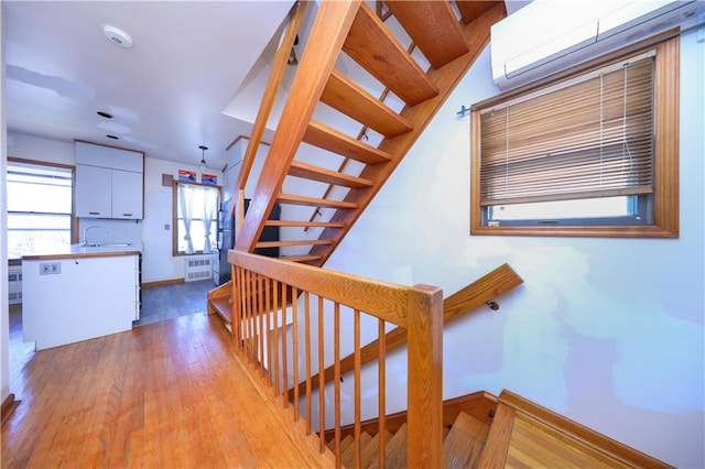 stairway with hardwood / wood-style flooring, radiator, baseboards, and a wall mounted air conditioner