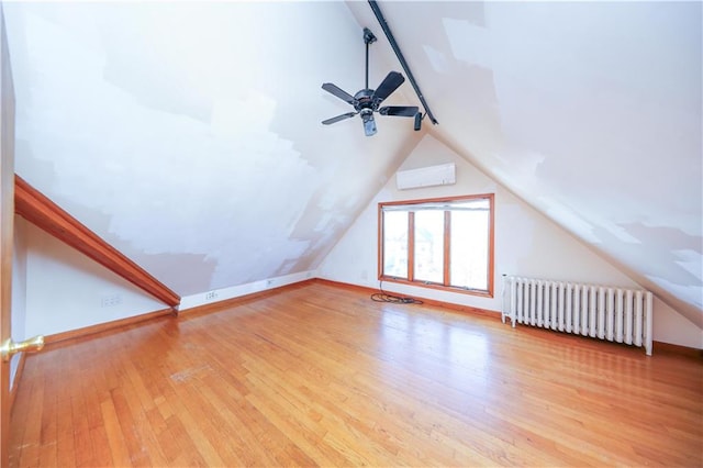 additional living space featuring vaulted ceiling, radiator, baseboards, and wood-type flooring