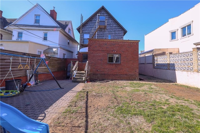 rear view of property with fence and brick siding