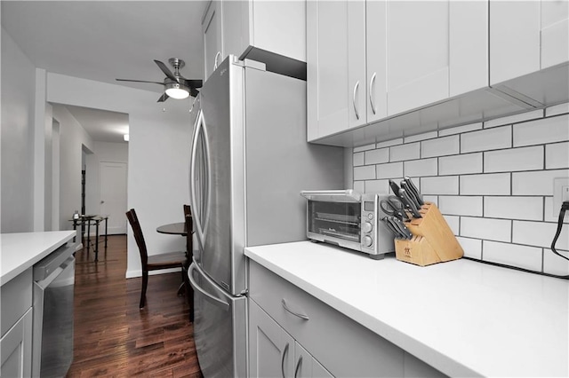 kitchen with dark wood-style floors, light countertops, backsplash, appliances with stainless steel finishes, and a ceiling fan