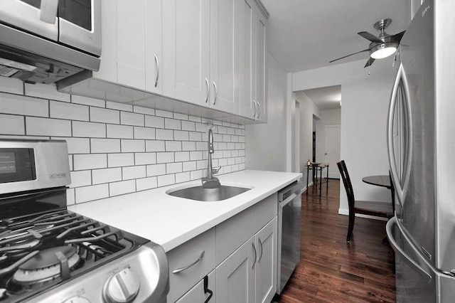 kitchen featuring dark wood finished floors, ceiling fan, appliances with stainless steel finishes, light countertops, and a sink