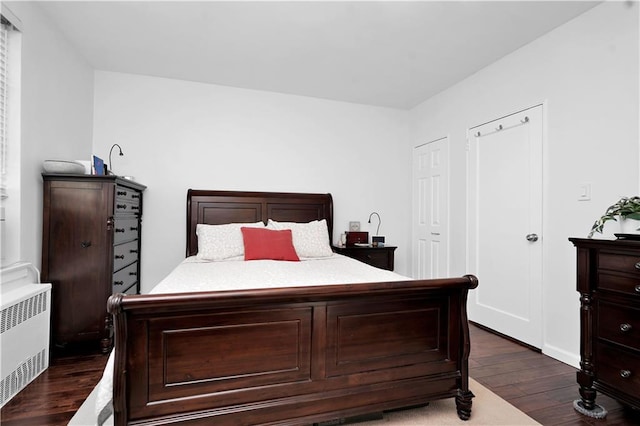 bedroom with dark wood-style flooring and radiator heating unit