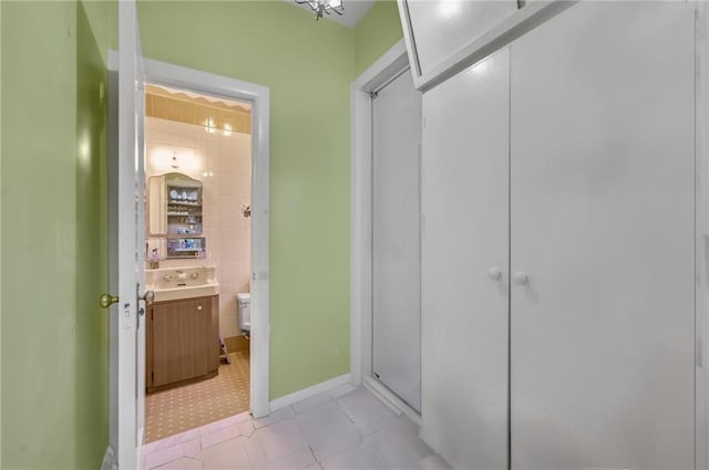 bathroom featuring vanity, toilet, baseboards, and a shower with shower door