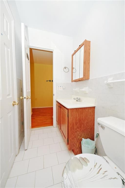 bathroom with tile walls, a wainscoted wall, toilet, and vanity