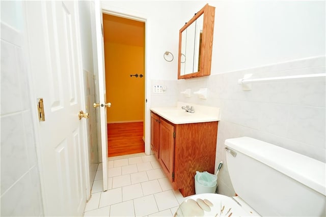 bathroom featuring tile walls, toilet, wainscoting, tile patterned floors, and vanity