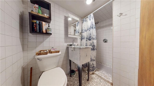 full bath with a tile shower, toilet, and tile walls