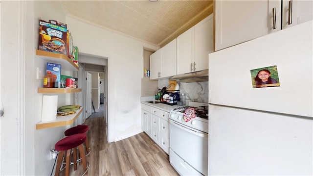 kitchen featuring white appliances, decorative backsplash, white cabinets, light wood-style floors, and under cabinet range hood