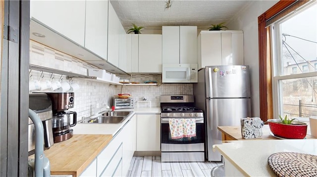 kitchen featuring tasteful backsplash, a sink, white cabinets, stainless steel appliances, and open shelves