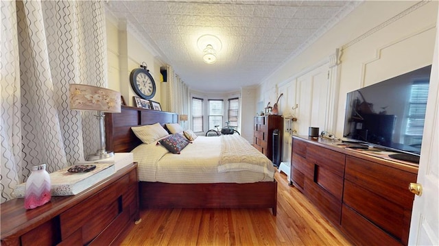 bedroom featuring light wood-type flooring and ornamental molding