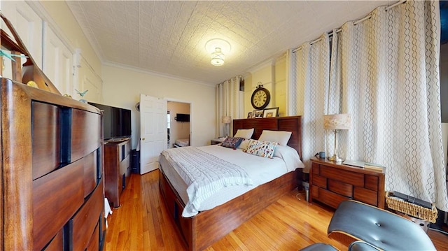 bedroom featuring wood finished floors, an ornate ceiling, and ornamental molding