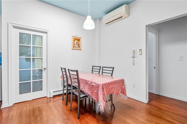 dining space with baseboard heating, an AC wall unit, baseboards, and wood finished floors