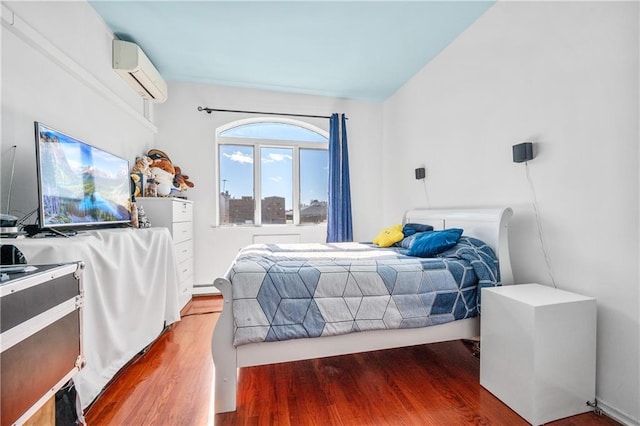 bedroom with an AC wall unit, wood finished floors, and a baseboard radiator