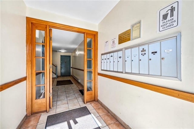 hallway featuring light tile patterned floors, mail area, a baseboard heating unit, and baseboards