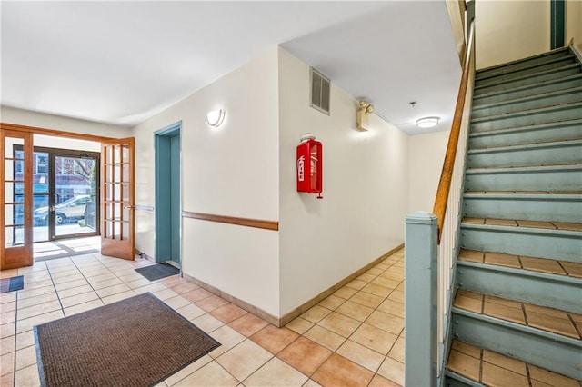 interior space with french doors, baseboards, visible vents, and tile patterned flooring