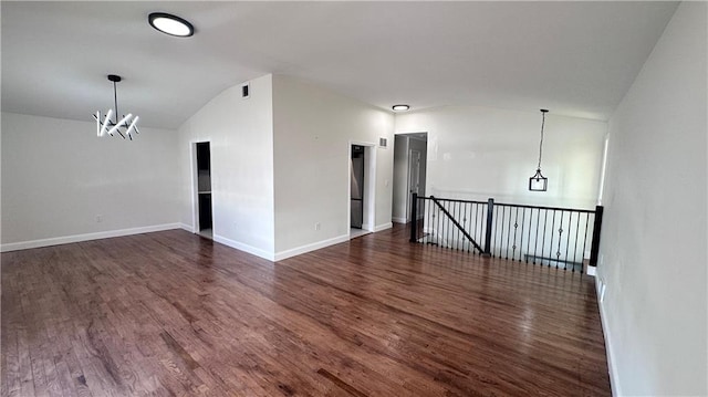 spare room with a chandelier, wood finished floors, baseboards, and vaulted ceiling