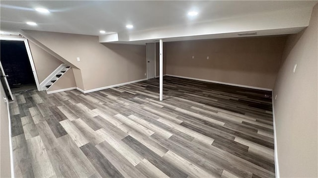 finished basement with visible vents, baseboards, stairway, recessed lighting, and wood finished floors