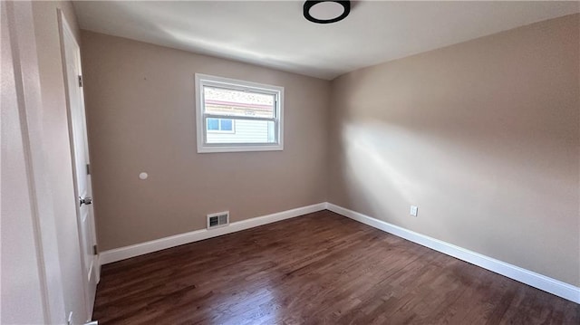 spare room with baseboards, visible vents, and dark wood-style flooring