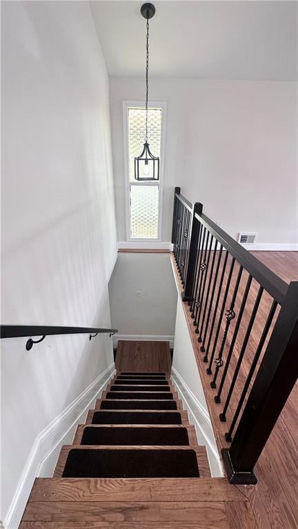 stairway with wood finished floors and baseboards