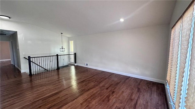 unfurnished room with baseboards, wood finished floors, and vaulted ceiling