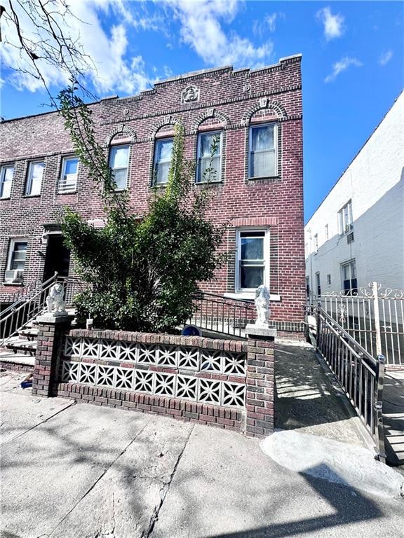 view of property featuring brick siding and fence