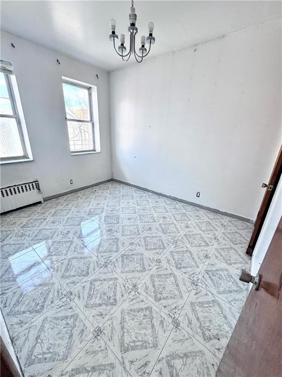 spare room featuring a notable chandelier and baseboard heating