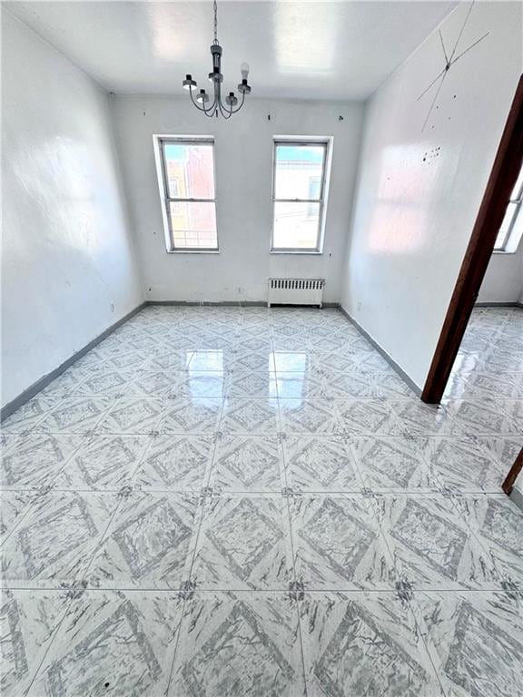 unfurnished room with radiator heating unit, baseboards, and a chandelier