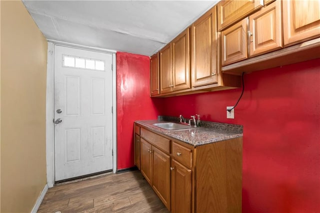 laundry area featuring wood finished floors, baseboards, and a sink