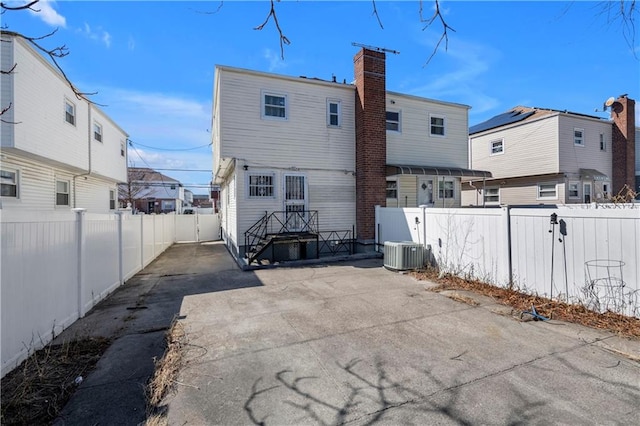 rear view of property featuring a patio area, a chimney, and a fenced backyard