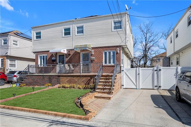 view of front of house with brick siding, a front lawn, and a gate