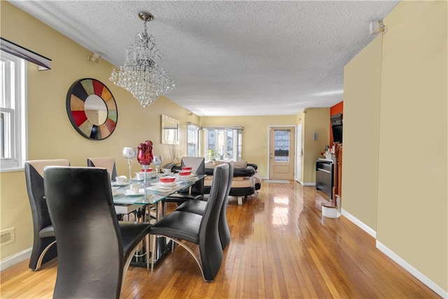 dining space with light wood-type flooring, baseboards, and a notable chandelier