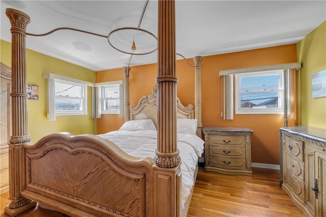 bedroom with baseboards, light wood-style flooring, and ornate columns