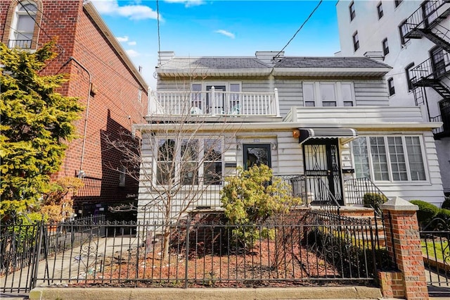 view of front of house featuring a balcony and a fenced front yard