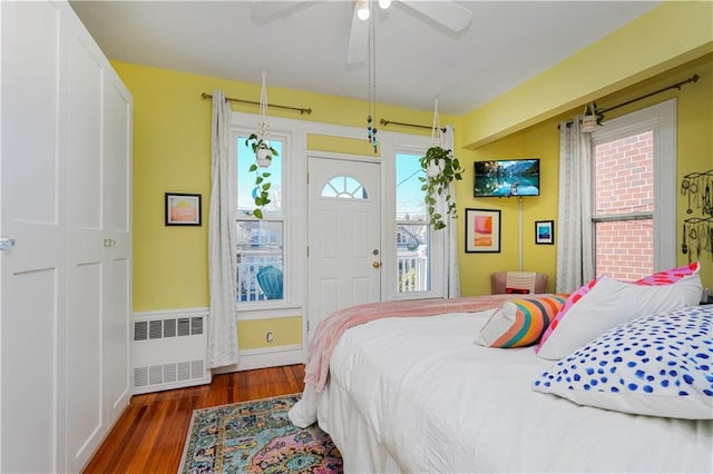 bedroom with ceiling fan, baseboards, radiator, and wood finished floors