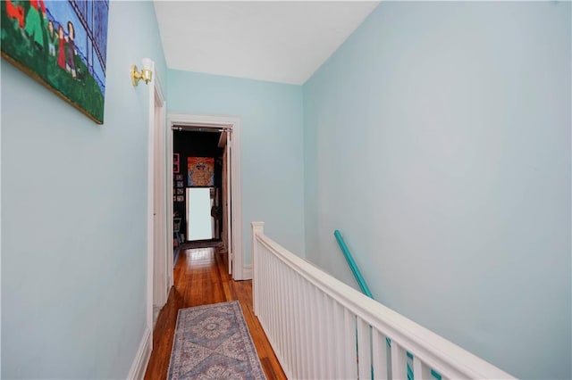 hall with an upstairs landing and wood finished floors