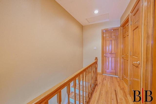 hall with an upstairs landing, recessed lighting, attic access, and light wood-style floors