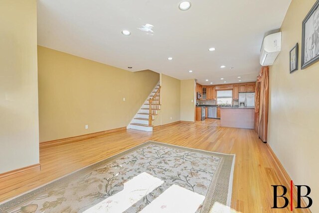 living area with recessed lighting, light wood-style flooring, stairs, and baseboards