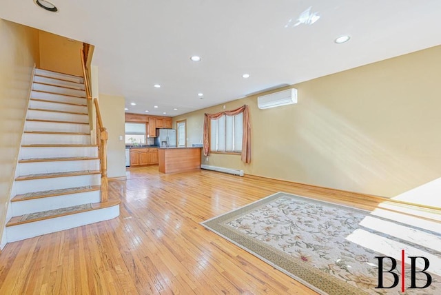 unfurnished living room featuring light wood-style flooring, recessed lighting, stairs, an AC wall unit, and a baseboard heating unit