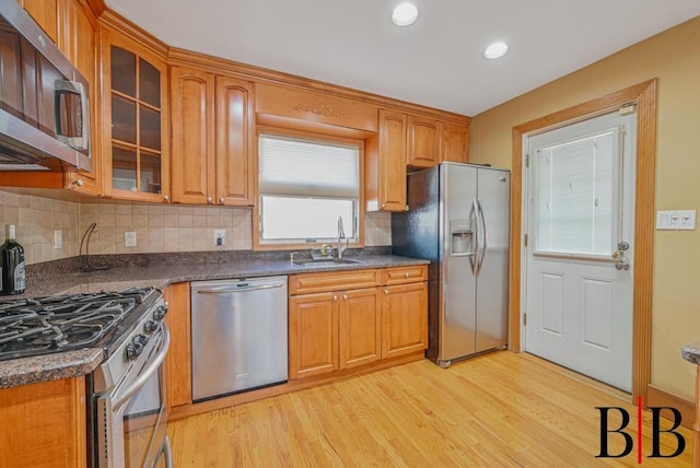 kitchen with a sink, dark countertops, light wood finished floors, and stainless steel appliances