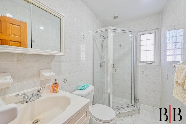 full bath with tile patterned flooring, toilet, vanity, a stall shower, and tile walls