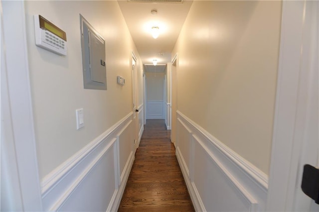 hallway with dark wood-style floors, attic access, electric panel, wainscoting, and a decorative wall