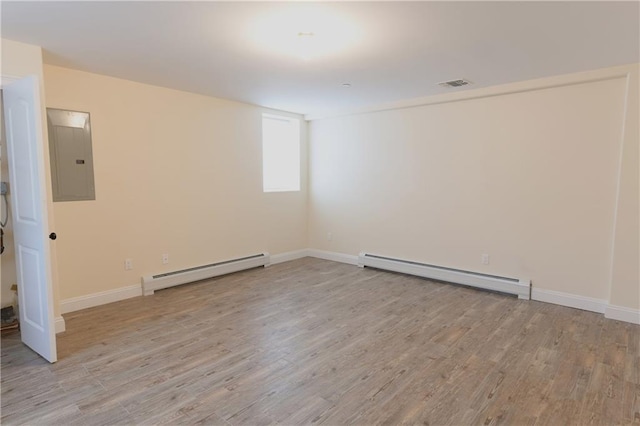 unfurnished room with a baseboard heating unit, light wood finished floors, electric panel, and baseboards