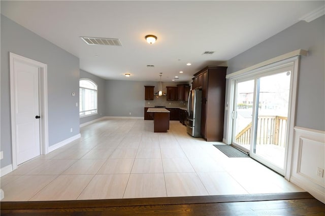 kitchen with open floor plan, visible vents, freestanding refrigerator, and a center island