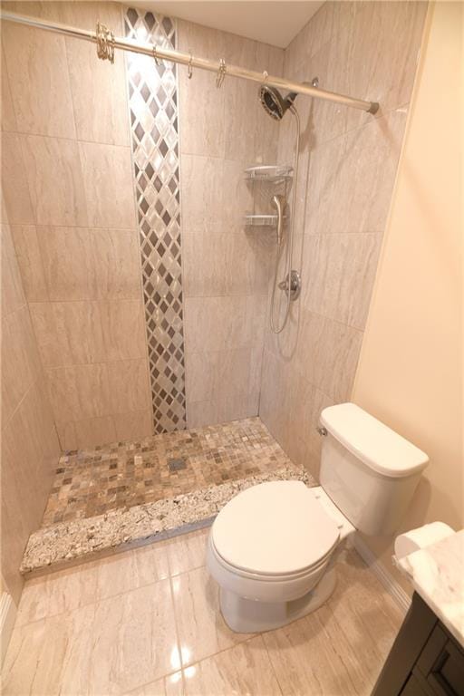 bathroom featuring toilet, vanity, and a tile shower